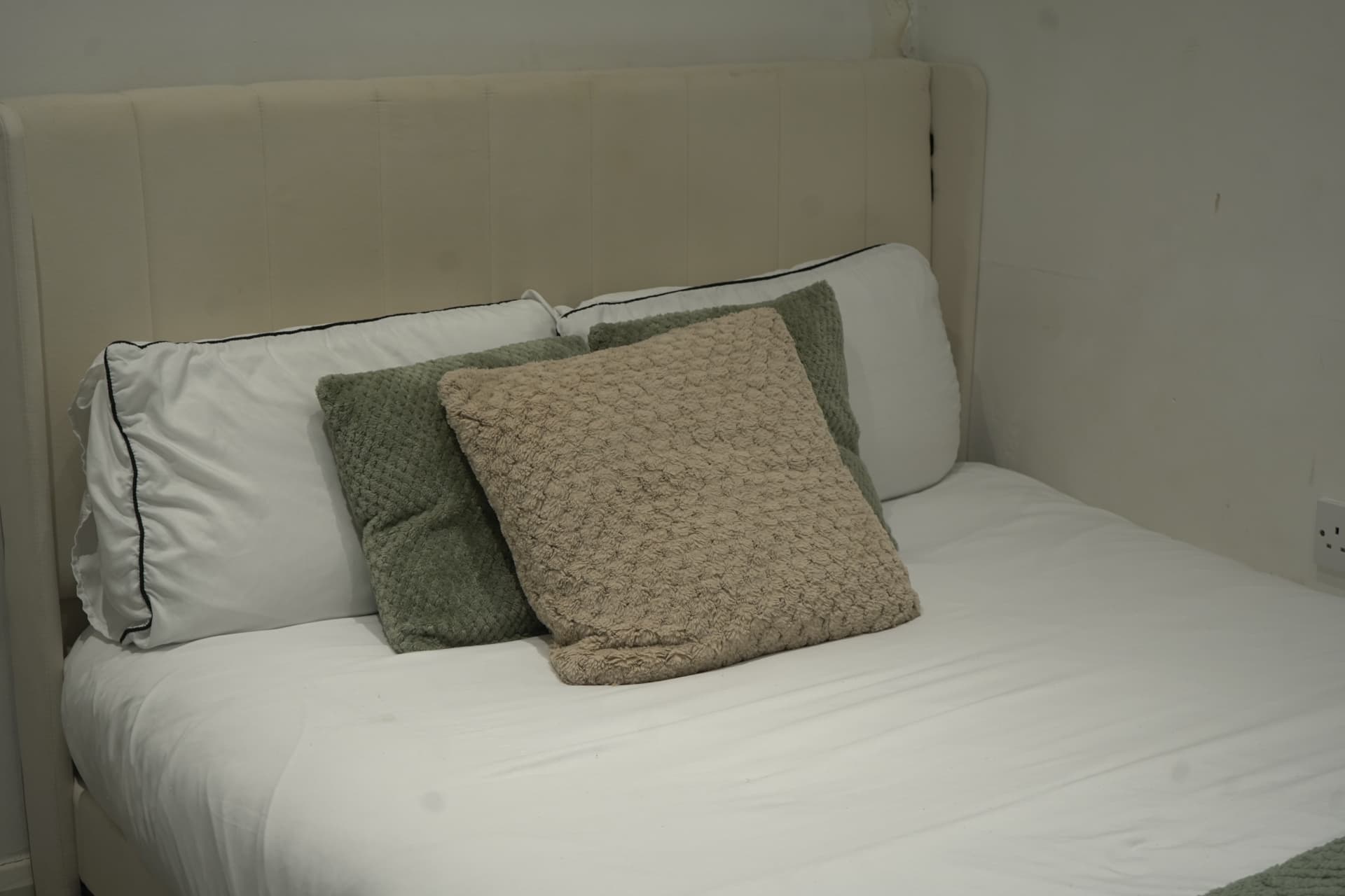 A freshly made bed with cushions neatly arranged